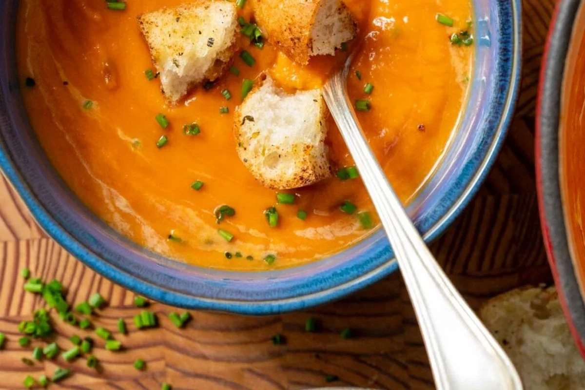Belizean Beef and Bean Soup Recipe: A Traditional Caribbean Comfort Dish 1 A bowl of creamy, vibrant orange butternut squash and tomato soup garnished with fresh herbs.