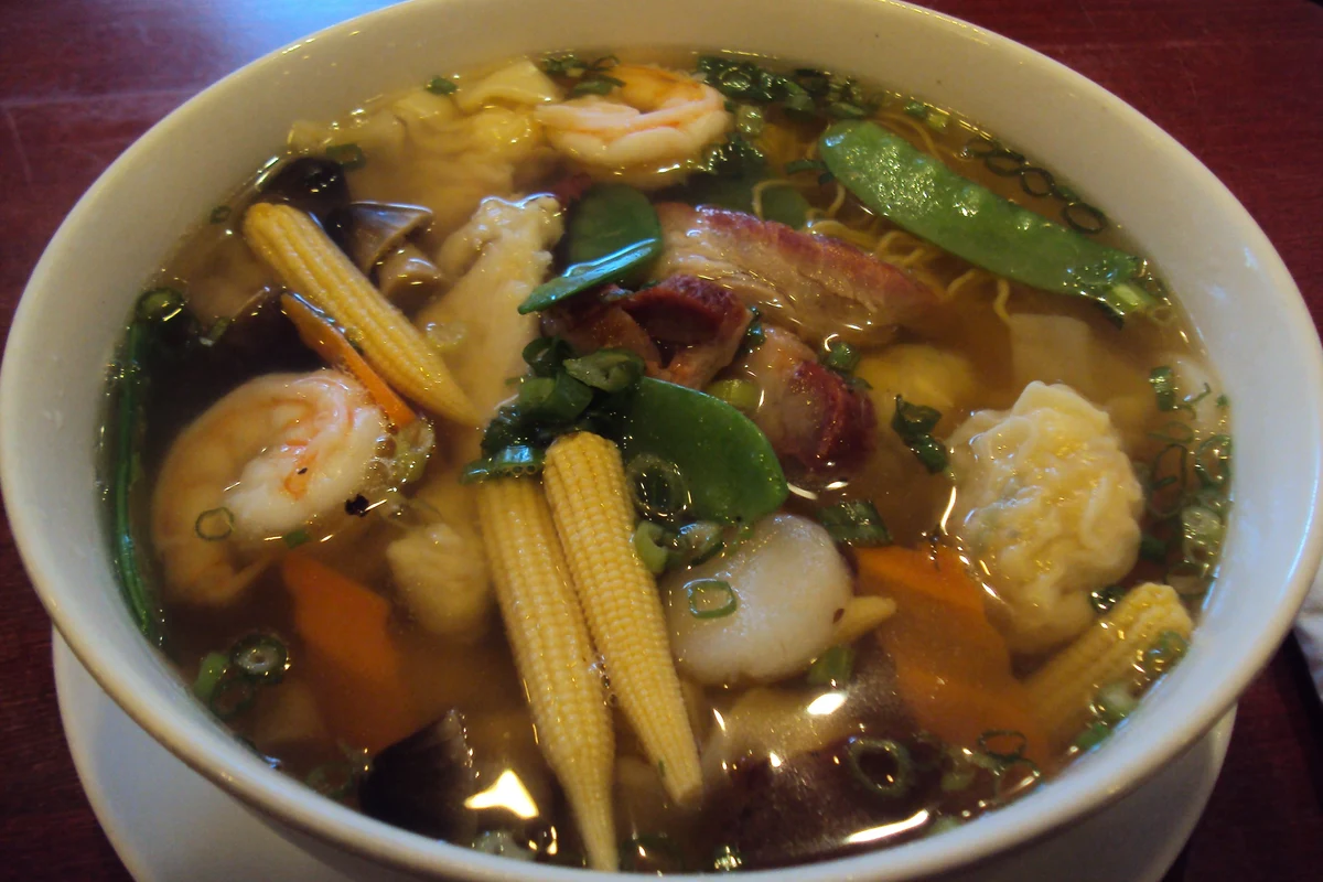 A steaming bowl of Chinese House Special Soup featuring shrimp, sliced pork, bok choy, and ginger in a clear broth.