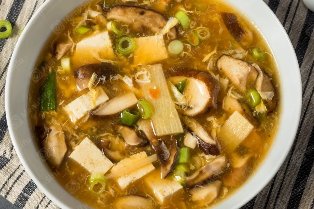 A steaming bowl of Chinese House Special Soup featuring shrimp, sliced pork, bok choy, and ginger in a clear broth.