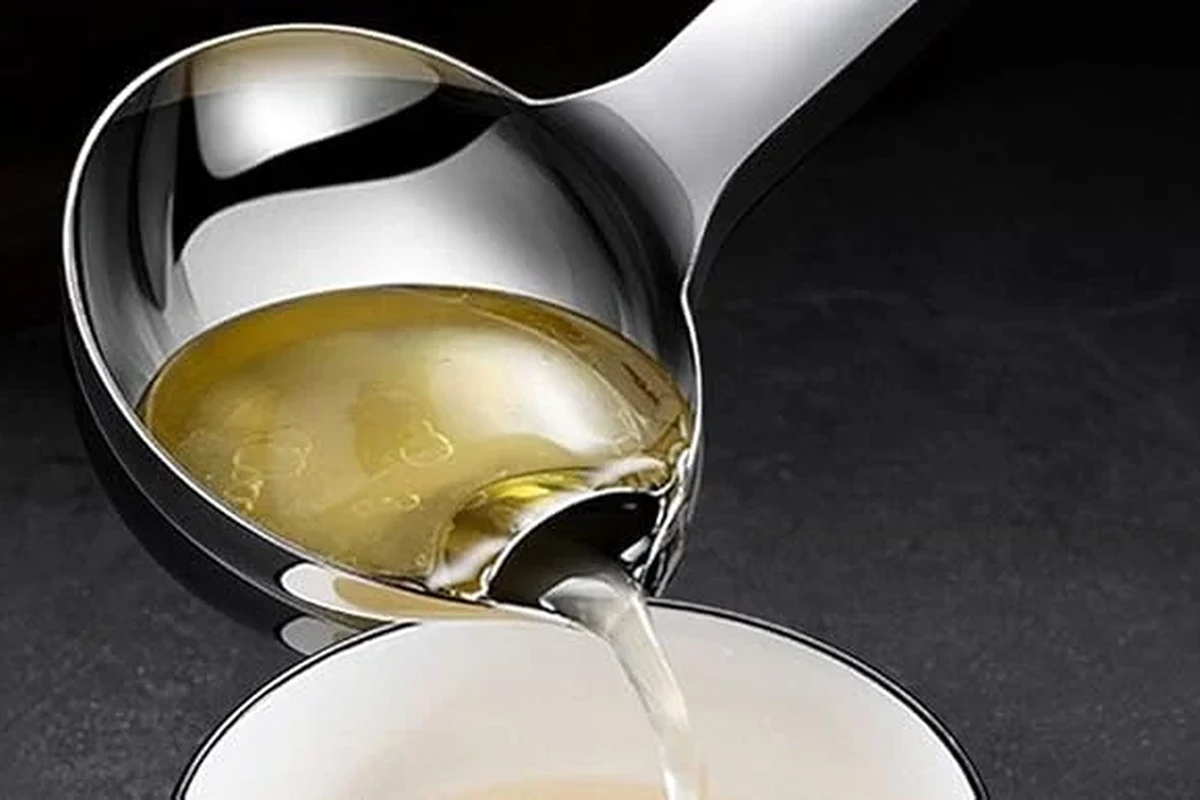 Fatsoff Soup Scoop: A Guide for Belizean Kitchens 2026 3 A person using a specialized Fatsoff soup scoop to skim excess fat from a large pot of traditional Belizean cow foot soup.