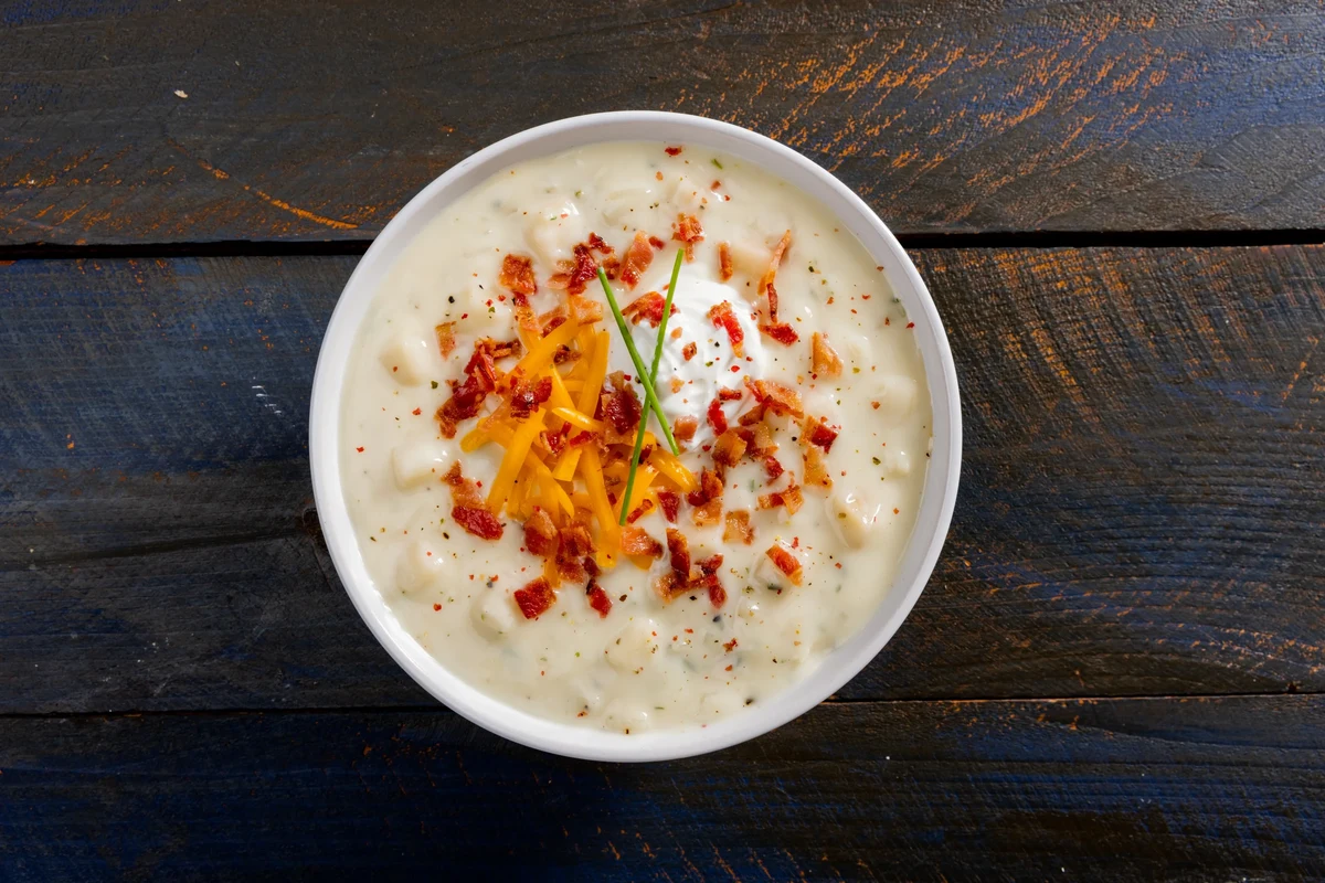 Potato Soup Mix: How to Make It Better + Storage & Cooking Tips (2026) 3 A steaming bowl of creamy potato soup garnished with fresh herbs, with a wooden spoon and rustic kitchen ingredients nearby.