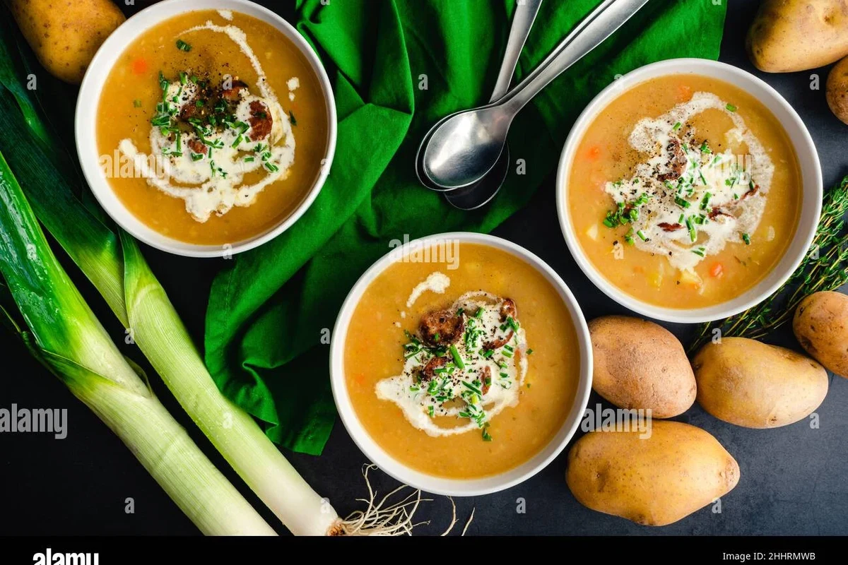 Sausage Potato Leek Soup Recipe (Easy, Creamy & Hearty One-Pot Meal) 2 A steaming bowl of creamy sausage, potato, and leek soup garnished with fresh herbs in a rustic kitchen setting.