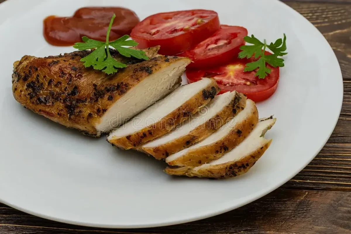 A perfectly pan-seared 12 oz chicken breast with herbs on a wooden cutting board.