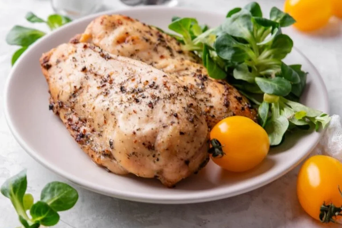 Broiled Chicken Breast 2 Golden-brown broiled chicken breast on a wire rack with fresh herbs and lime wedges.