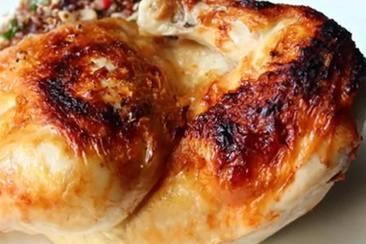 A perfectly charred piece of broiled chicken with a golden-brown glaze, served on a rustic plate.