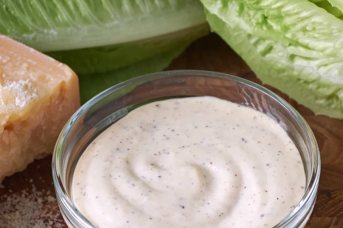 Caesar Dressing with Anchovy Paste 2 Creamy Caesar dressing with anchovy paste in a small glass bowl next to fresh romaine lettuce.