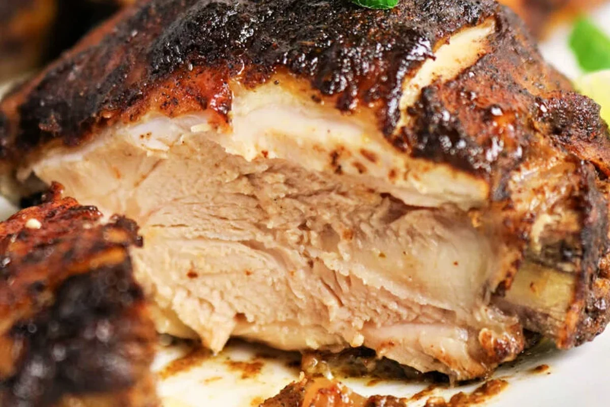 Golden brown oven-baked jerk chicken served on a wire rack with fresh thyme and scotch bonnet peppers.