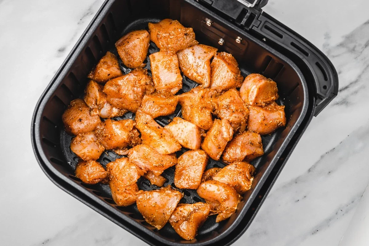 Golden brown cubed chicken cooked in an air fryer with seasoning, served in a bowl.