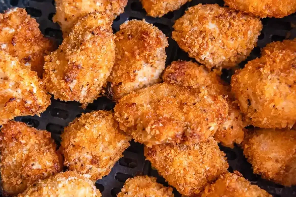 Golden brown cubed chicken cooked in an air fryer with seasoning, served in a bowl.