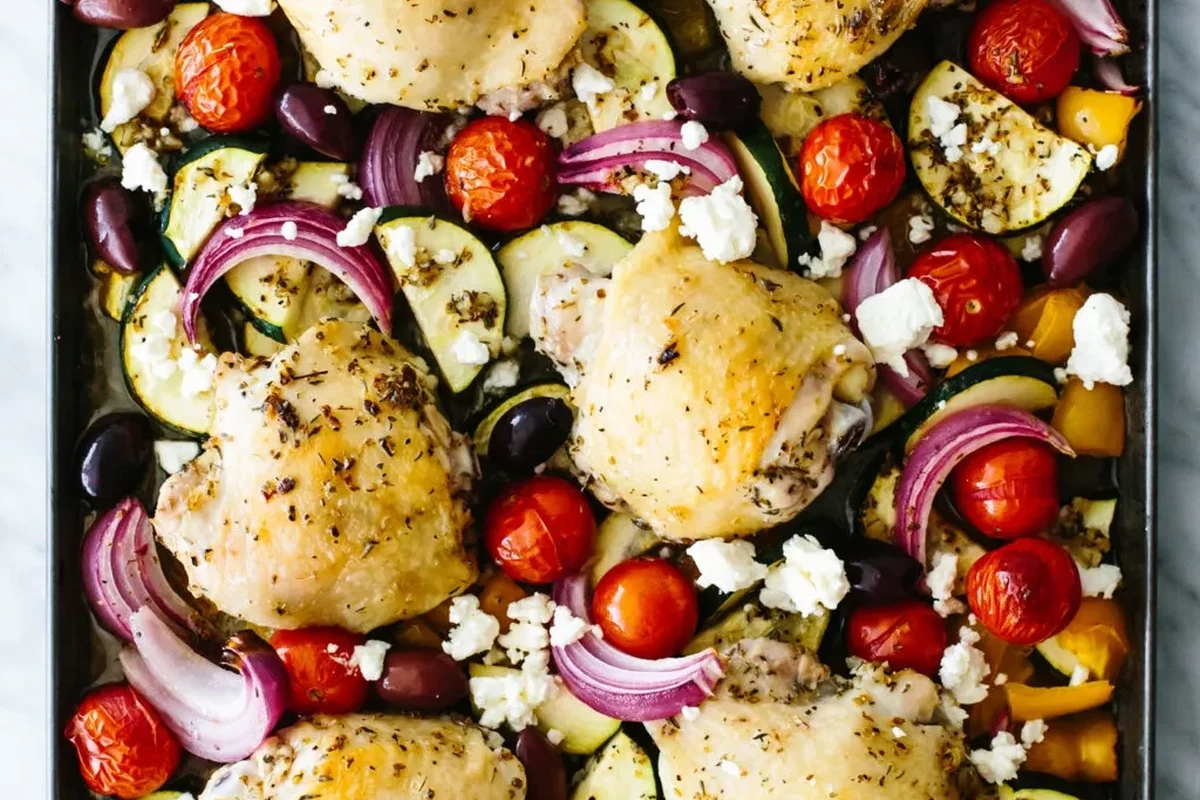Greek Sheet Pan Chicken 2 A colorful sheet pan featuring roasted chicken thighs, bell peppers, red onions, and kalamata olives, garnished with fresh he