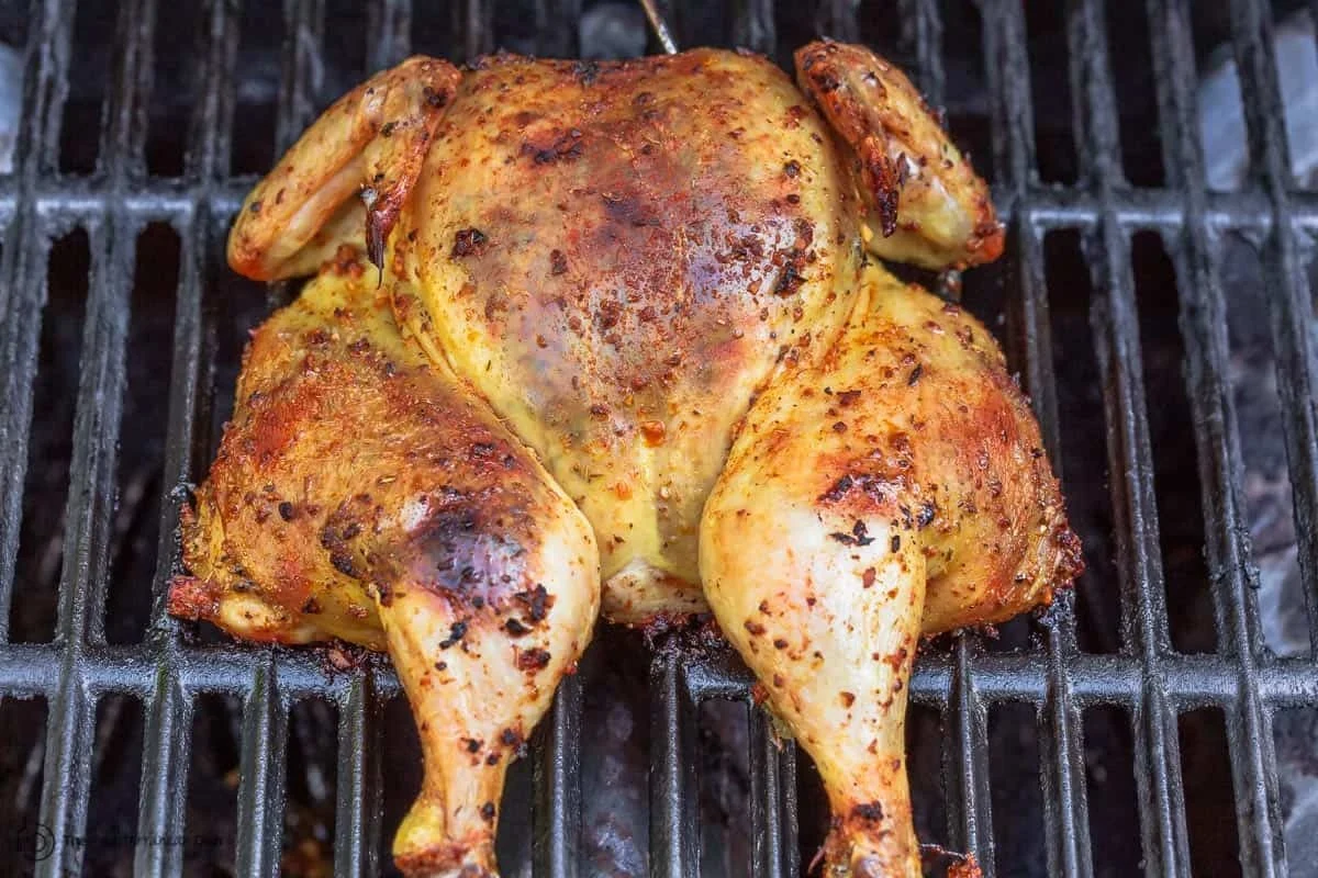 Grill Chicken in Oven 1 A golden-brown oven-grilled chicken leg quarter on a wire rack with a charred, flavorful crust.