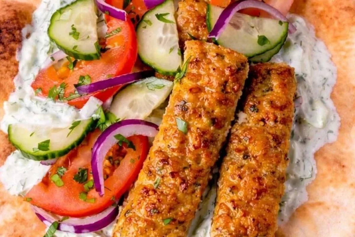 Grilled ground chicken kebabs on a platter with fresh lime and cilantro garnish.