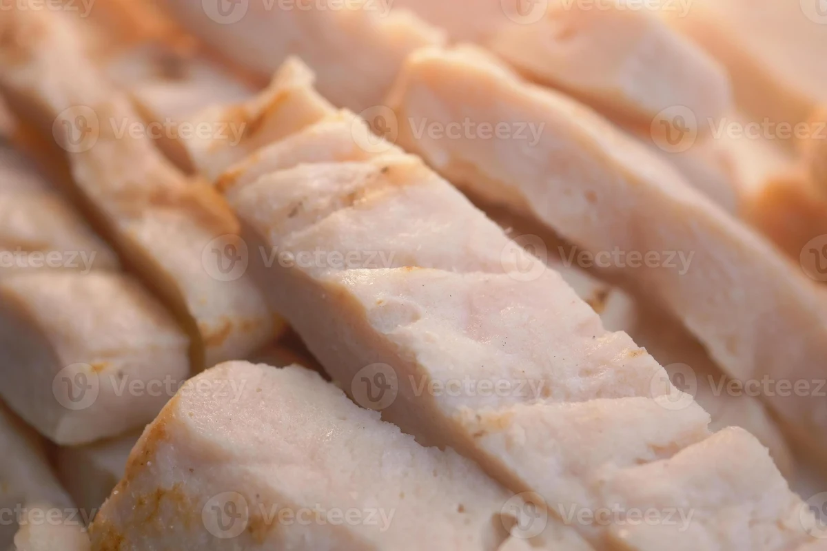 Fresh raw halved chicken breasts seasoned with spices on a wooden cutting board ready for cooking.