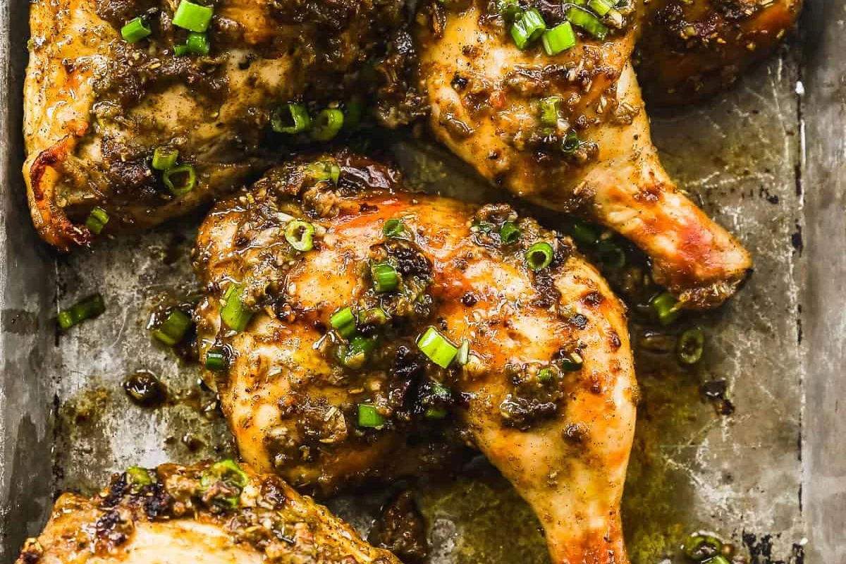 A platter of oven-baked Jamaican jerk chicken with a dark, caramelized spice crust and fresh thyme garnish.
