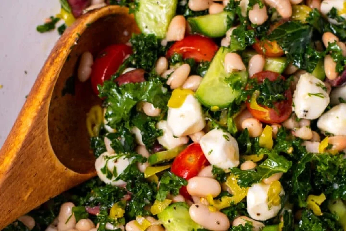 A fresh bowl of massaged kale and creamy cannellini beans tossed in a light vinaigrette with shaved parmesan.