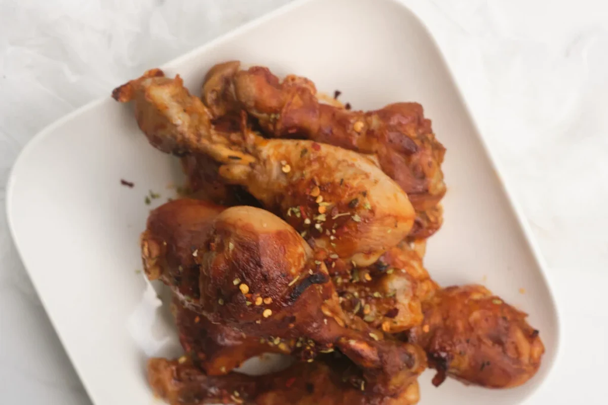 A pot of chicken legs simmering in a broth with aromatics like onions and carrots.
