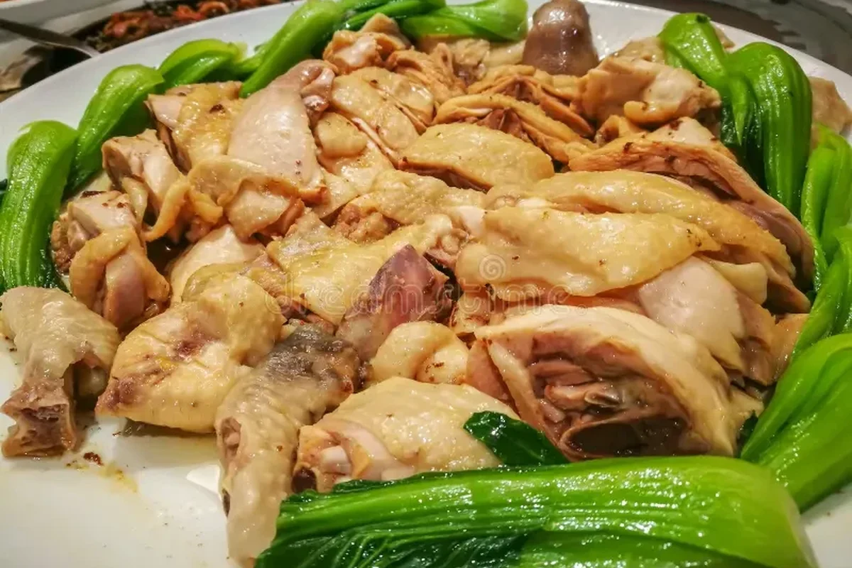How Long Should Chicken Be Boiled 1 Fresh chicken breasts being simmered in a pot with aromatics like onion and herbs.