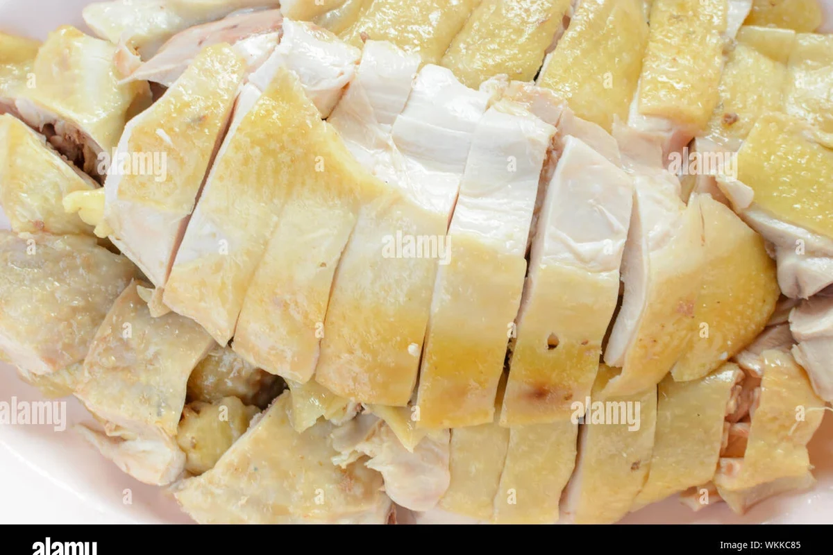 How Long Should Chicken Be Boiled 2 Fresh chicken breasts being simmered in a pot with aromatics like onion and herbs.