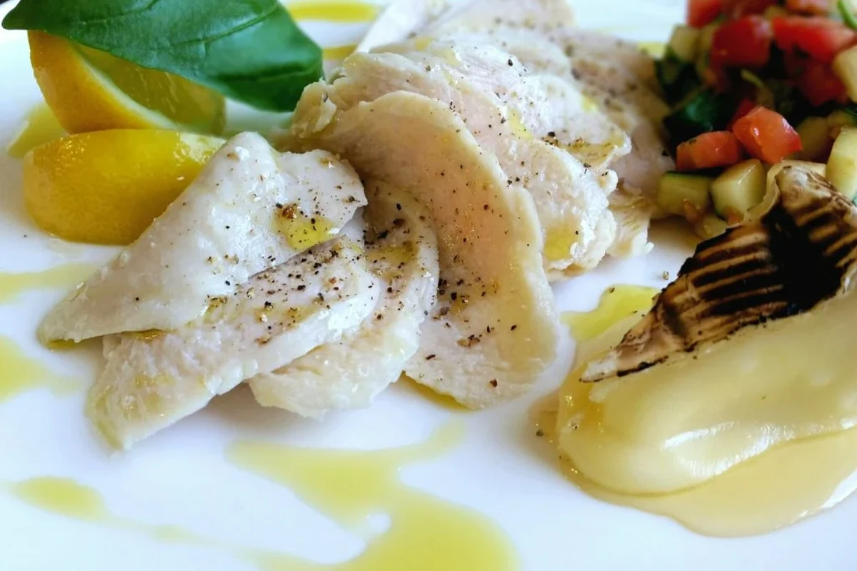 A golden-brown pan-seared chicken breast seasoned with herbs and finished with a drizzle of olive oil.