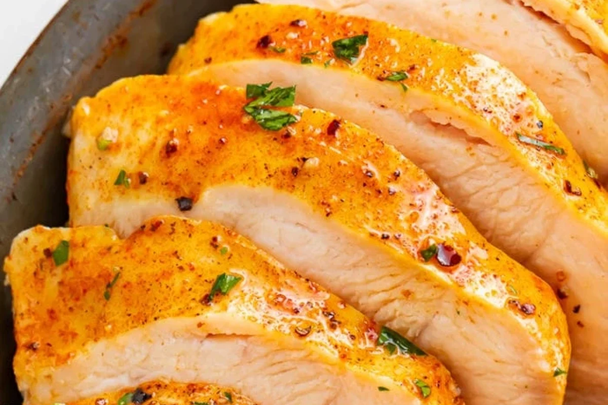 A stainless steel pressure cooker with cooked chicken breasts and aromatics inside.