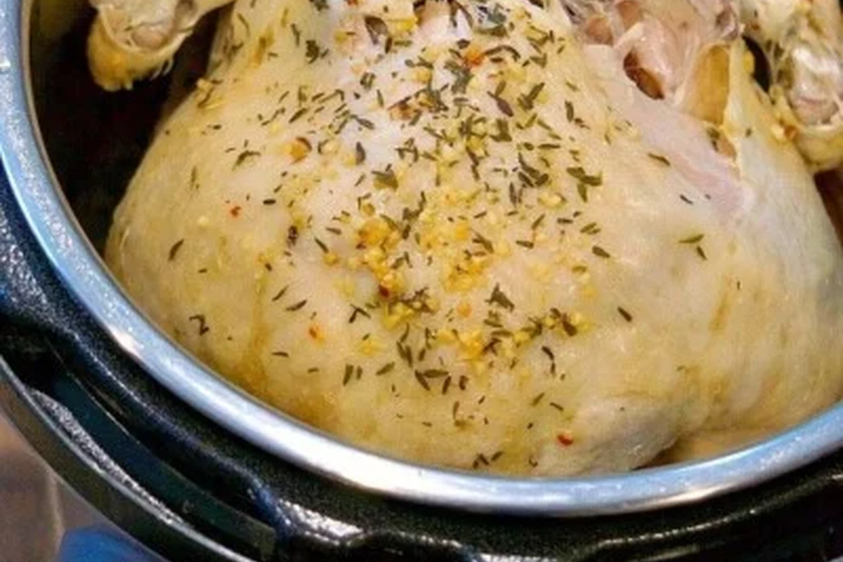 Tender, cooked chicken pieces in a pressure cooker with fresh herbs and broth.