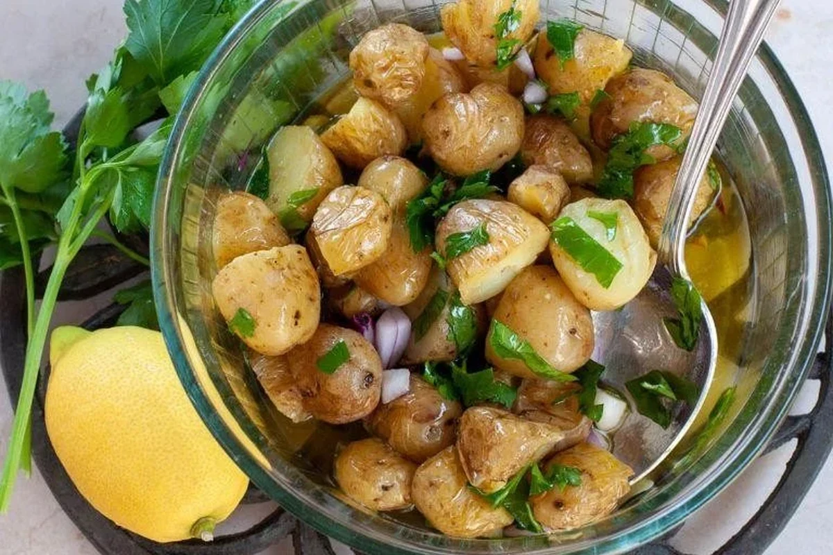 A rustic bowl of Sicilian potato salad with fresh parsley, olives, and a light olive oil dressing.